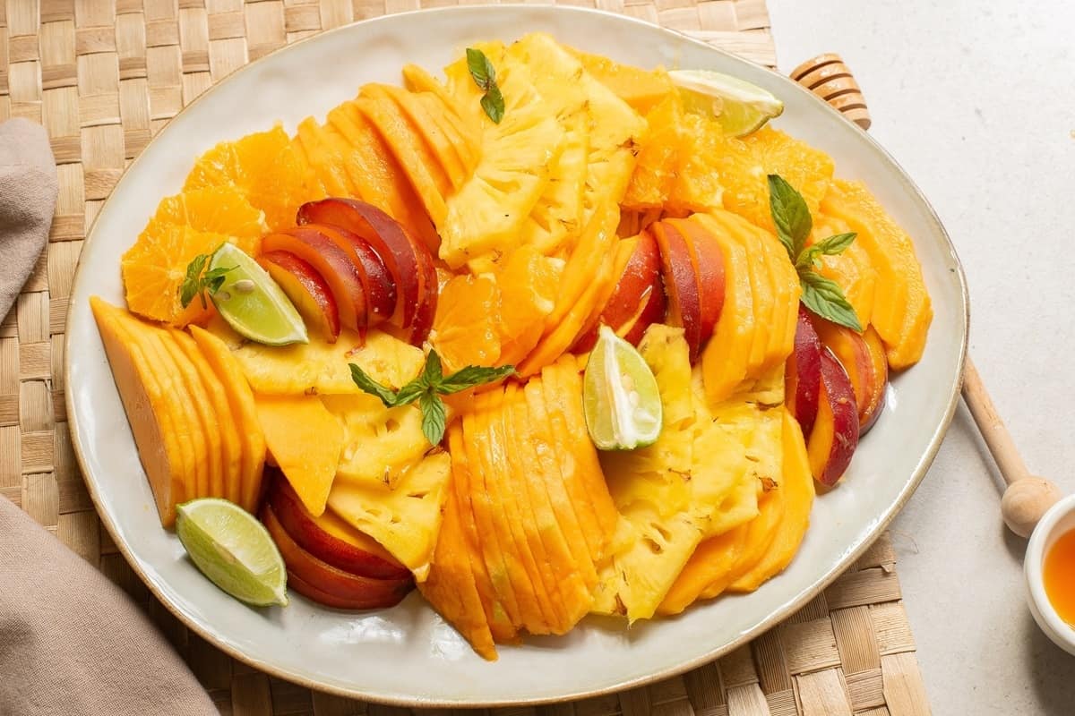 Mango slices on a plate with lime and honey.