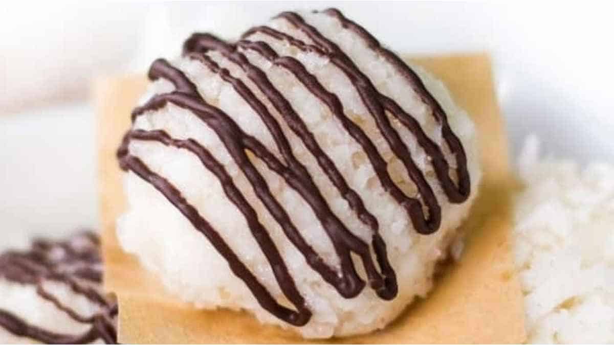 A white plate with a chocolate covered rice ball.