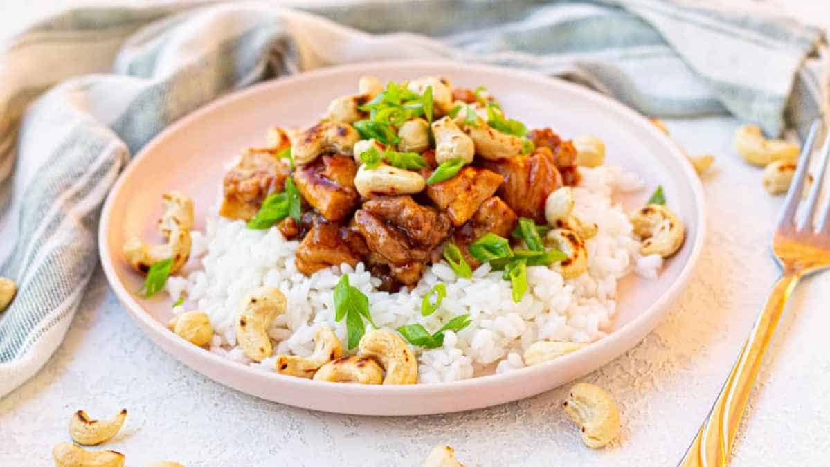 Plate of stir-fried chicken with cashews and green onions served over rice.
