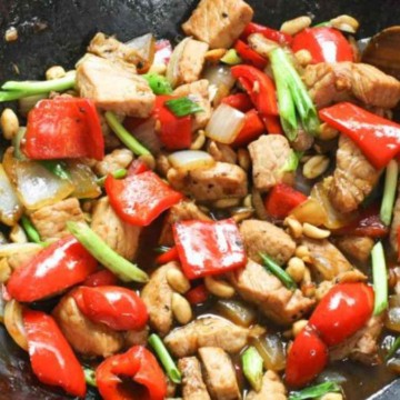 Stir-fried chicken and vegetables with peanuts in a wok.