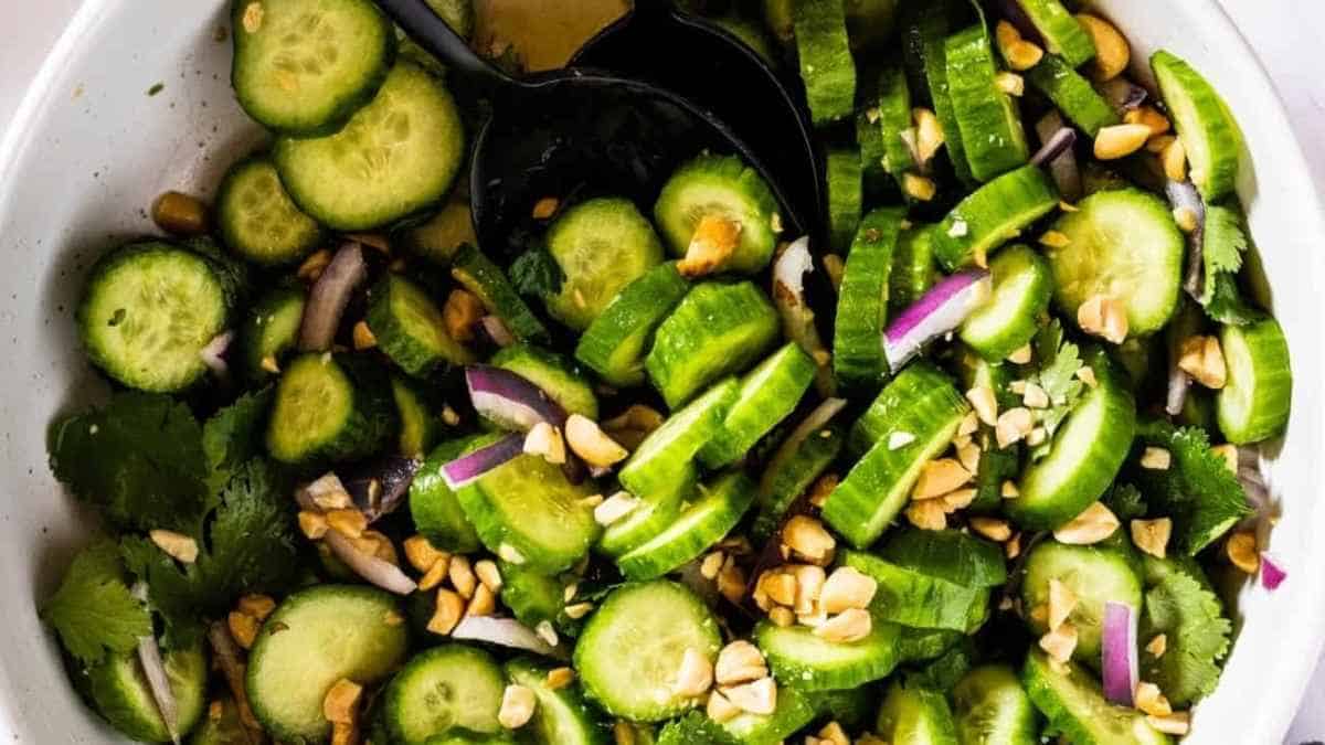 Cucumber salad with peanuts and onions in a white bowl.