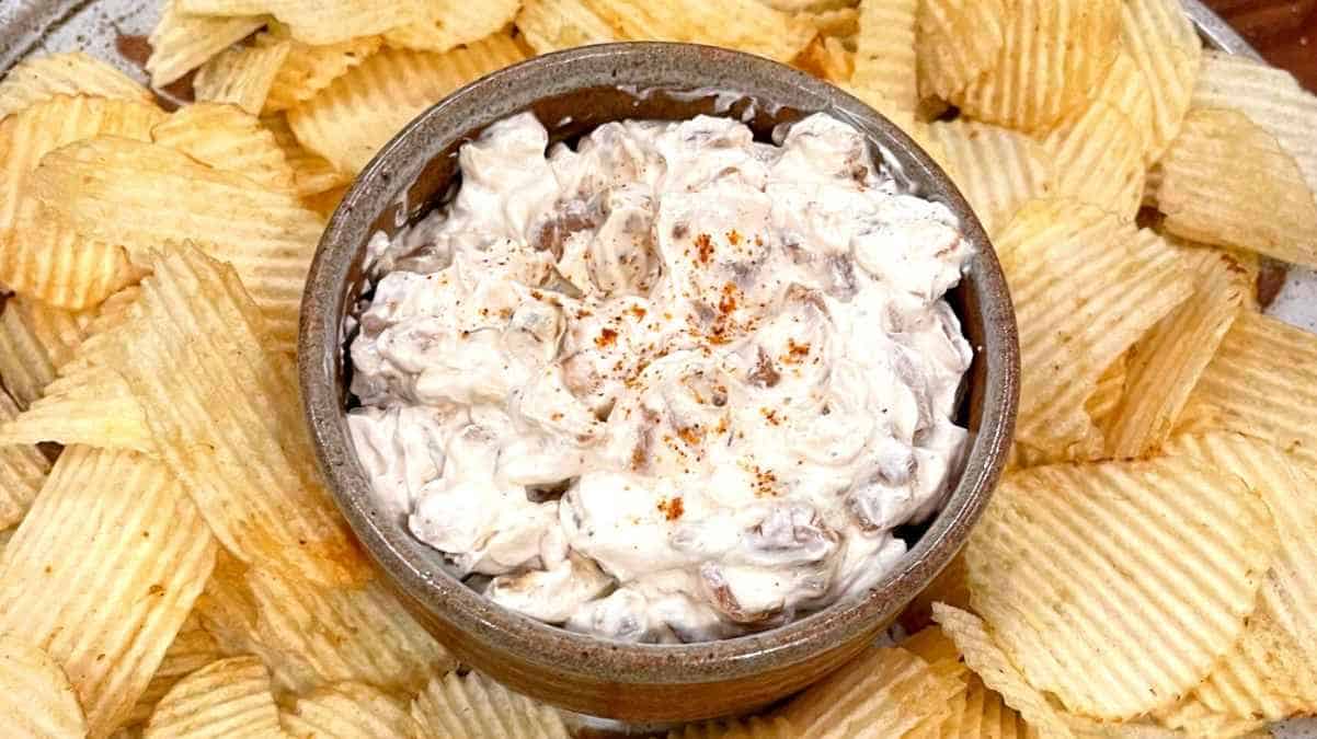 Bowl of onion dip surrounded by ridged potato chips.