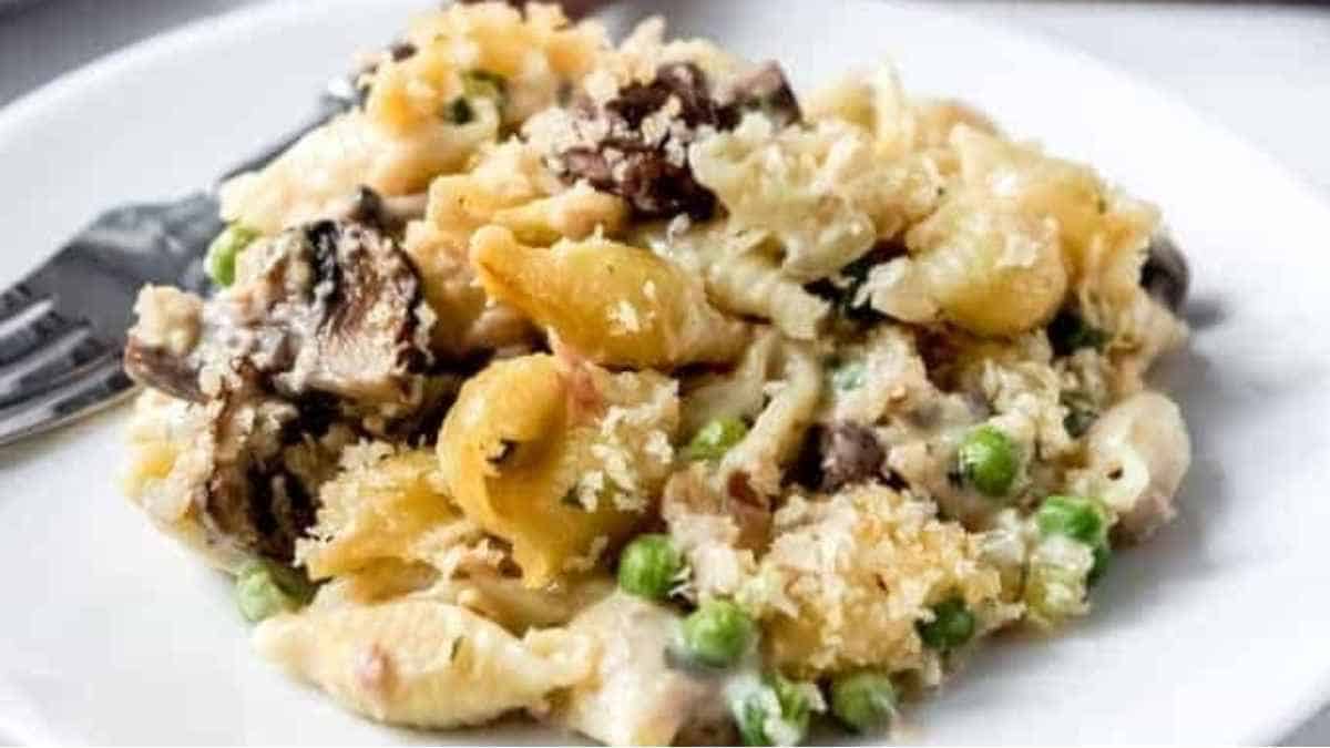 A plate of pasta with mushrooms and peas.