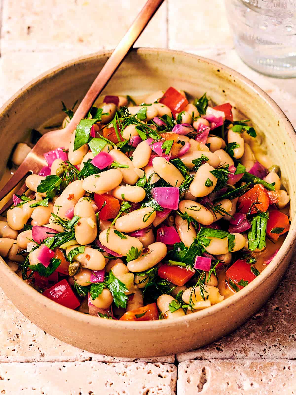 Tuscan bean salad with dill and bell peppers in a bowl. 
