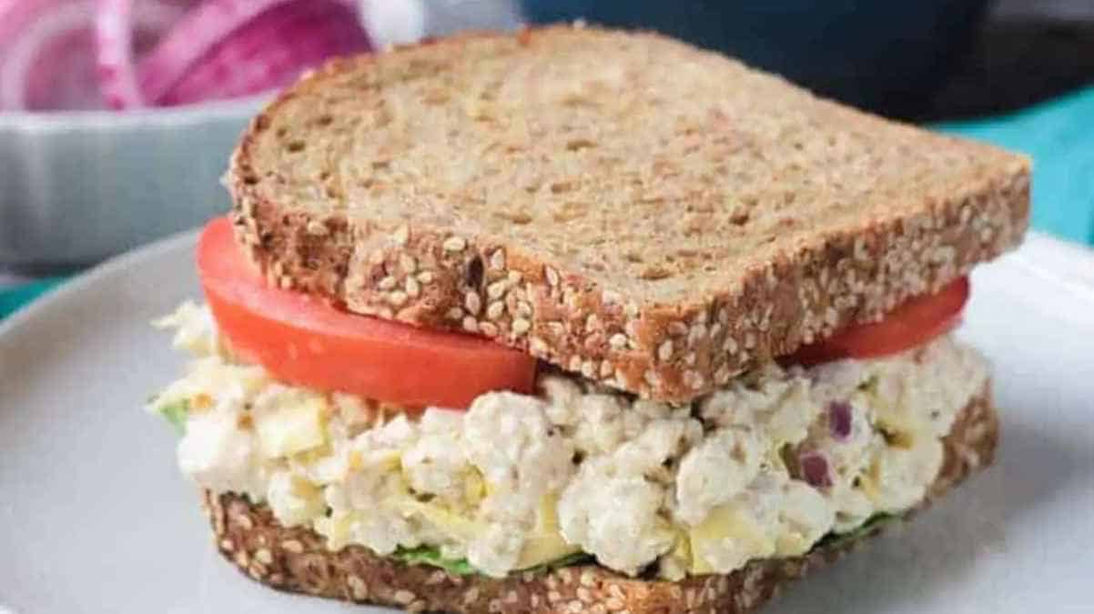 A whole grain sandwich with egg salad and tomato slices.