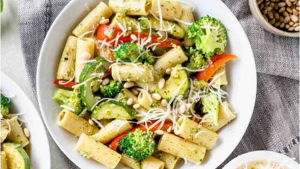 A bowl of pesto pasta with broccoli and peppers.