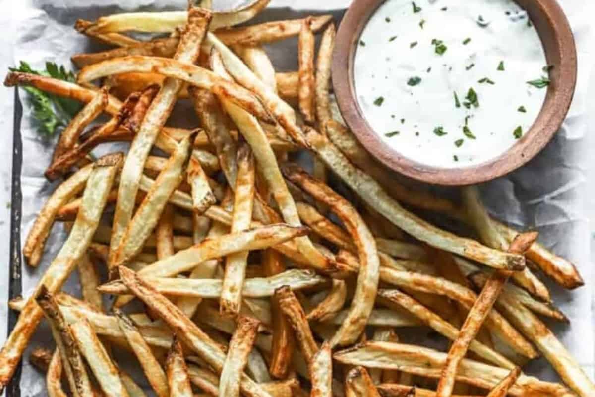 A plate of french fries with a bowl of dipping sauce.