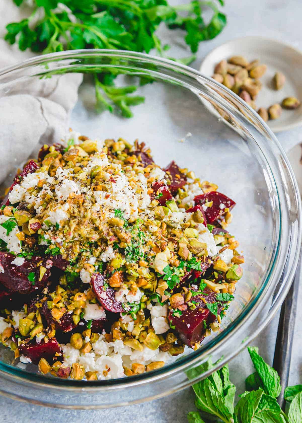 Tossing together the ingredients for a beet and feta cheese salad in a large glass bowl. / Tossing together the ingredients for a beet and feta cheese salad in a large glass bowl.
