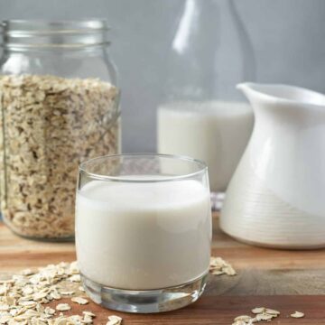 A glass of milk and oats on a wooden table, perfect for Vitamix recipes.
