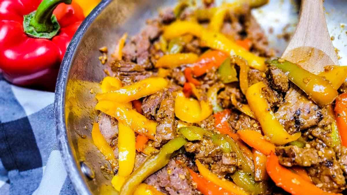 Sautéed beef and bell peppers in a skillet.