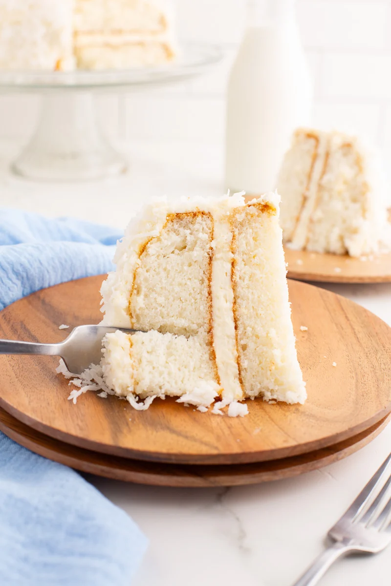 A fork cutting into a piece of coconut cake. 