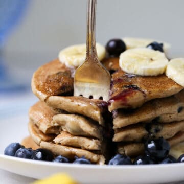 A stack of pancakes with blueberries and bananas on a plate, perfect for your Vitamix Recipes.