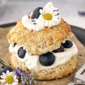 A fresh berry shortcake garnished with flowers, served on a rustic background.