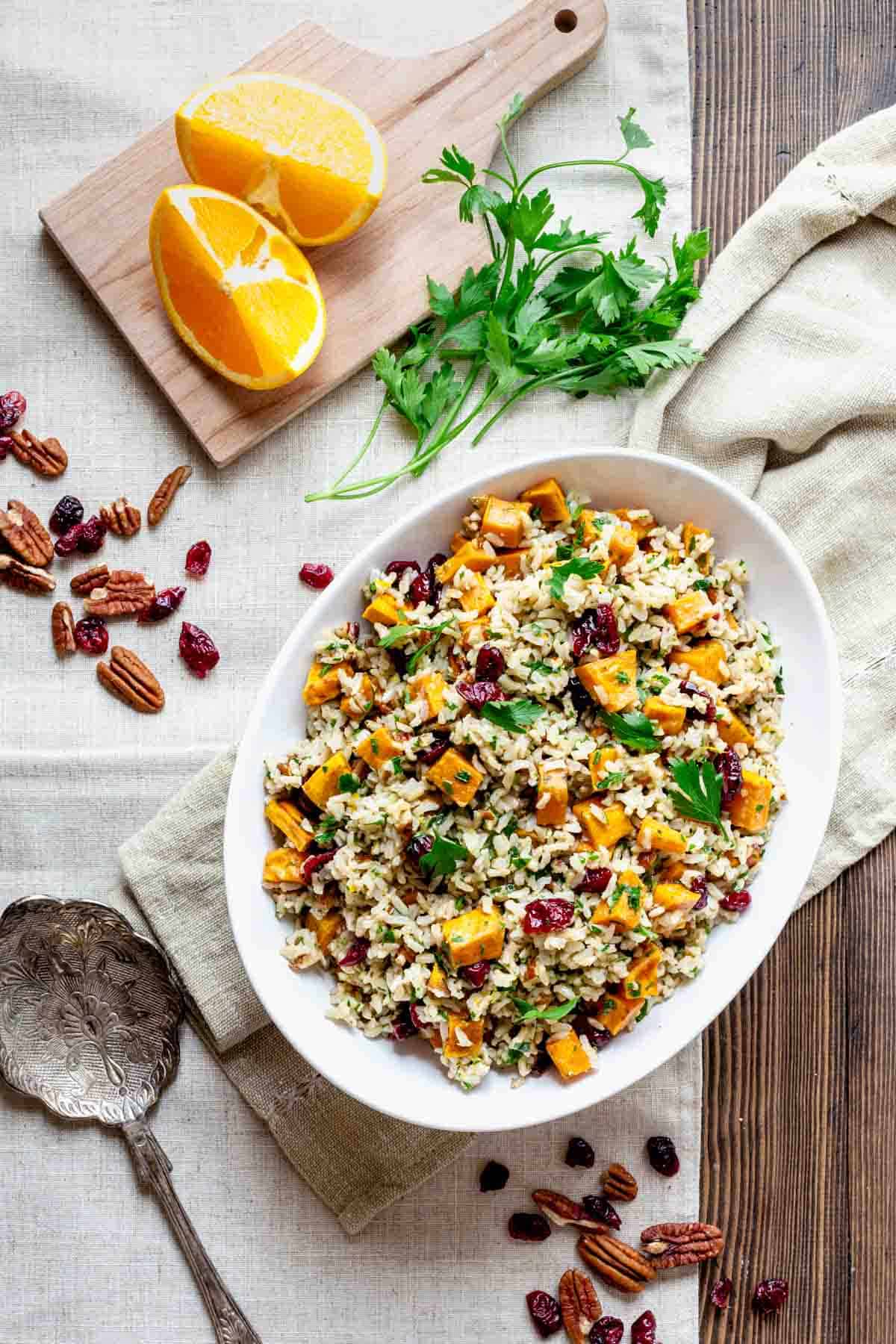 The salad with a cutting board with orange, pecans, cranberries and parsley.
