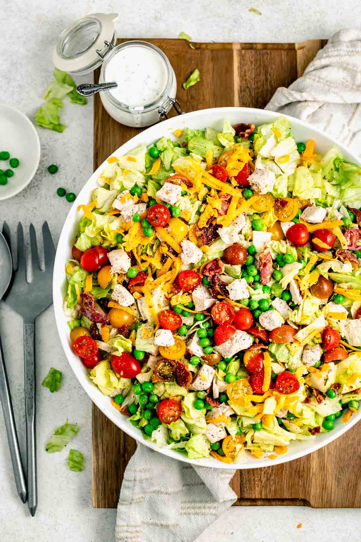 chopped salad with chicken in a bowl and mixed with peas, cheese, tomatoes, and lettuce.
