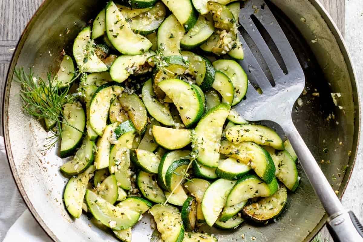 Zucchini with dill in a pan with a fork.