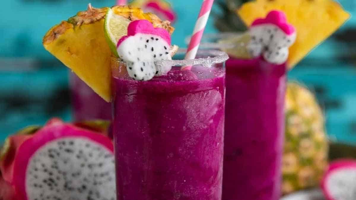 Tropical dragon fruit and pineapple cocktail with a striped straw.