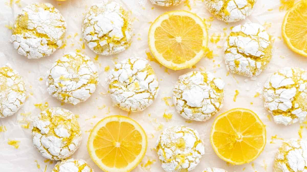 Lemon cookies with powdered sugar alongside fresh lemon slices on a light background.