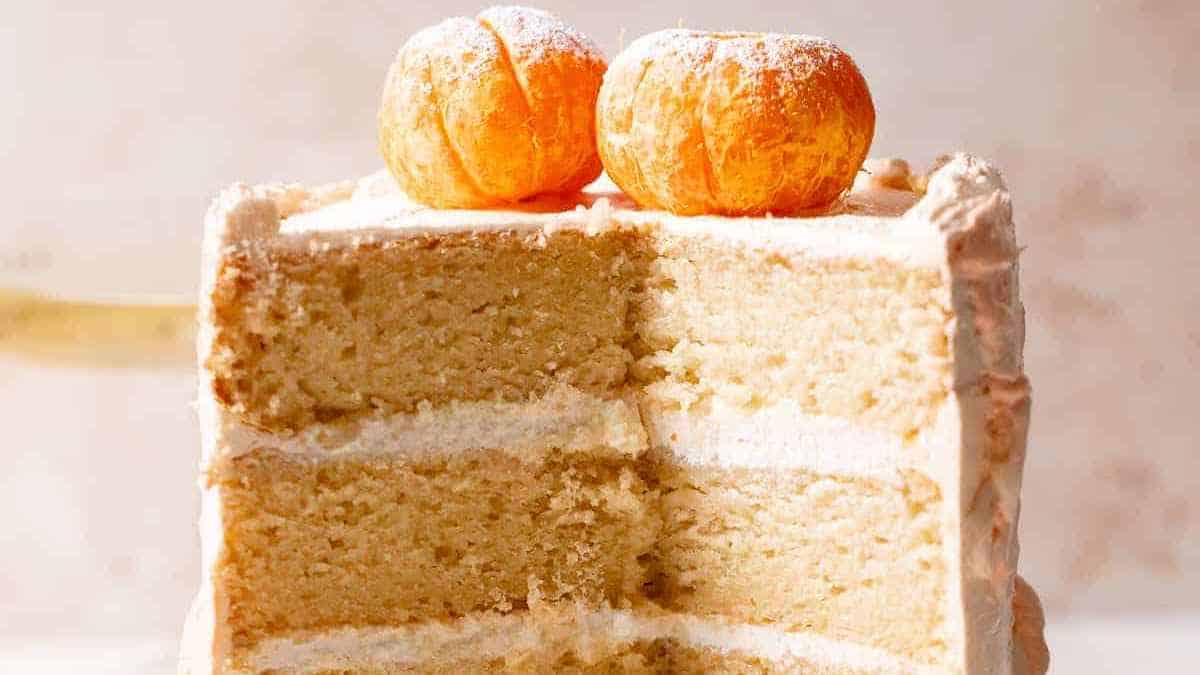 یک تکه کیک وانیلی چند لایه با فراستینگ، روی آن دو شیرینی گرد کوچک.
