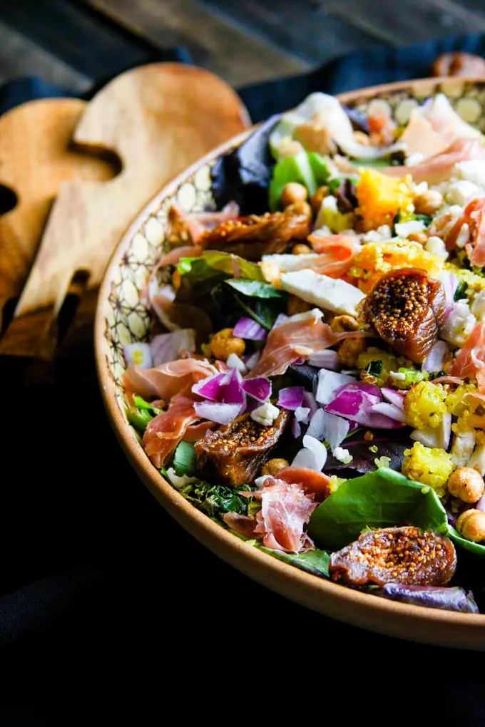 Close up view Moroccan salad in colorful bowl topped with figs. 
