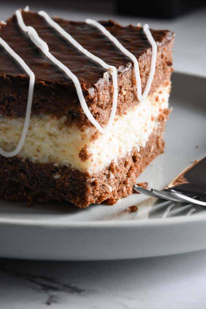 Sourdough coconut and chocolate cake square on a white plate with a fork. 
