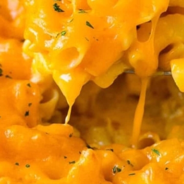 Creamy macaroni and cheese being lifted with a spoon, showcasing melted cheese.