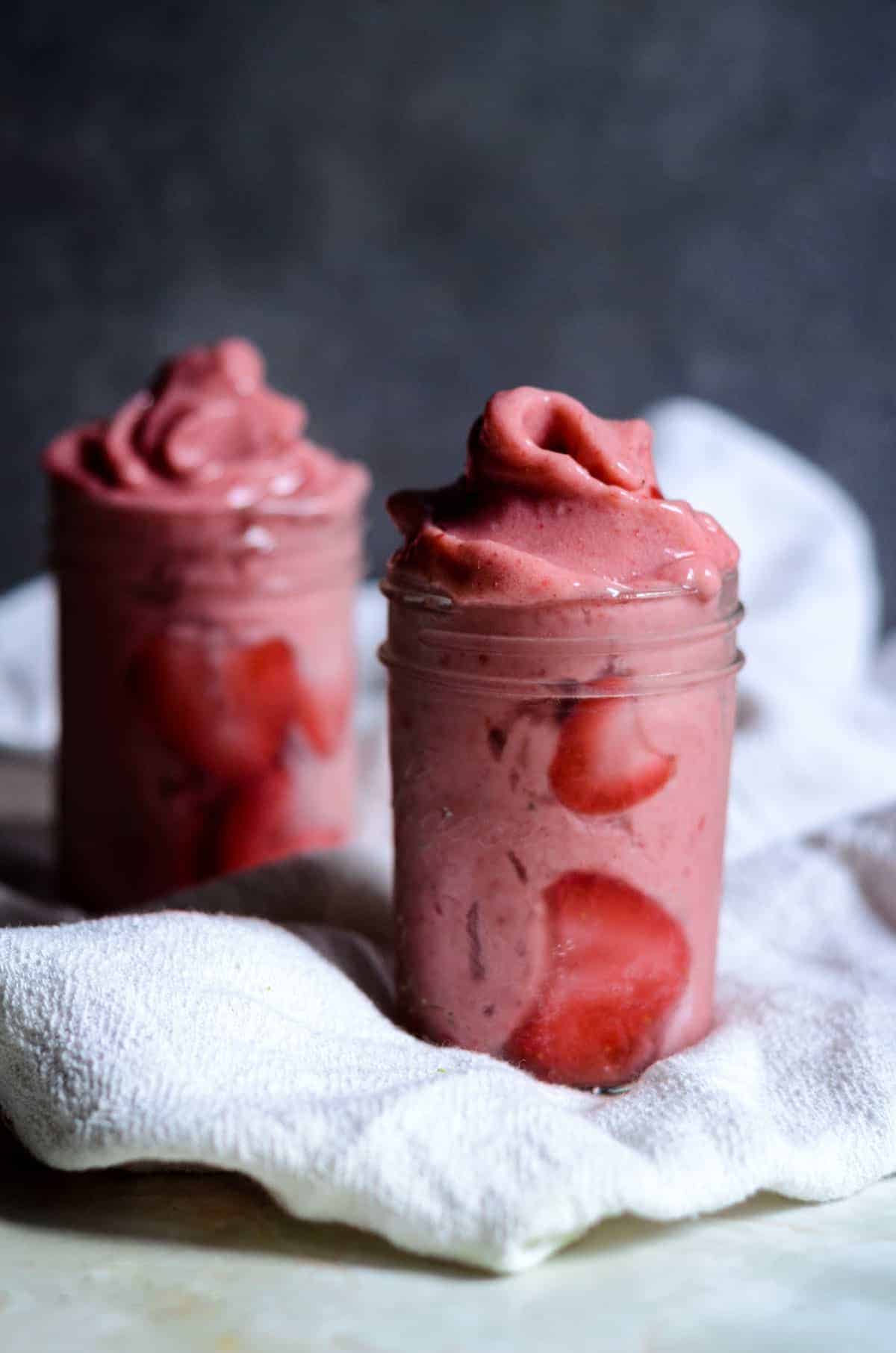 Two glass jars with food on a towel are featured in these Vitamix recipes.