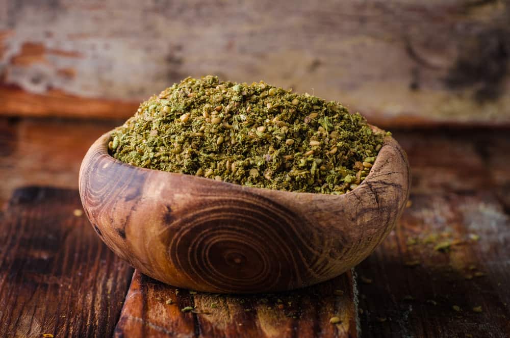 A wooden bowl filled with ground zucchini on a rustic wooden surface.