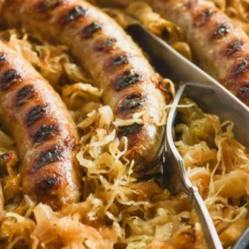 Grilled sausages served on a bed of sauerkraut in a skillet.