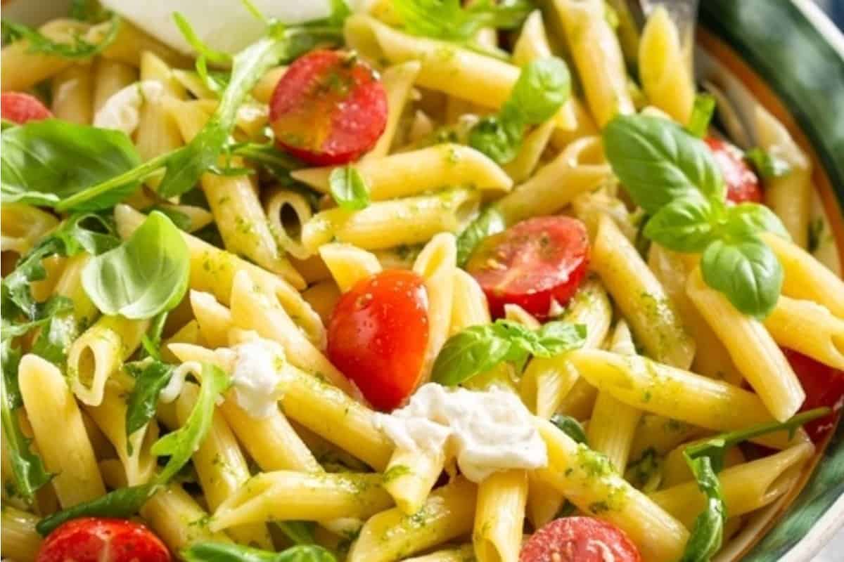 A bowl of penne pasta with cherry tomatoes, fresh basil, and dollops of ricotta cheese.