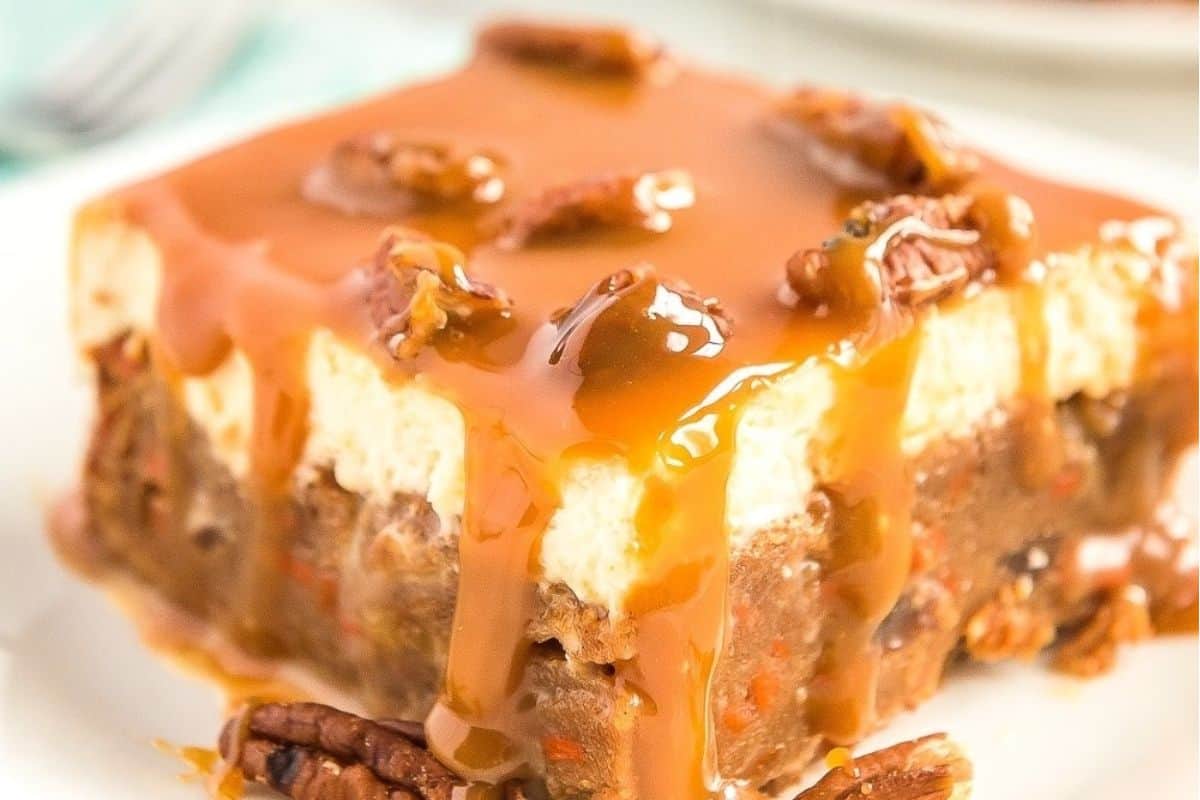 A slice of caramel drizzled dessert with pecans on top.