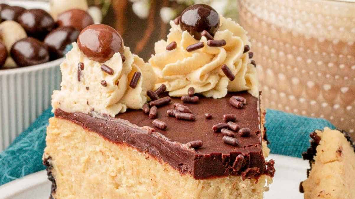 A slice of cake topped with chocolate ganache, whipped cream, sprinkles, and a chocolate ball.