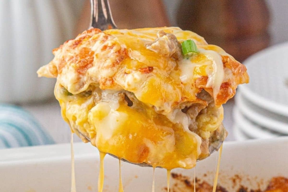 A fork lifting a cheesy portion of lasagna, showcasing the melted cheese stretching from the dish.