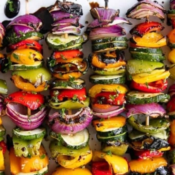 Colorful grilled vegetable skewers with bell peppers, zucchini, red onion, and mushrooms, drizzled with balsamic glaze.