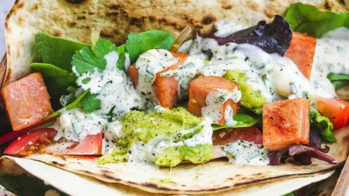 A colorful vegetable wrap drizzled with creamy sauce.