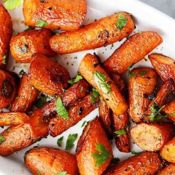 A plate of roasted carrots garnished with parsley.