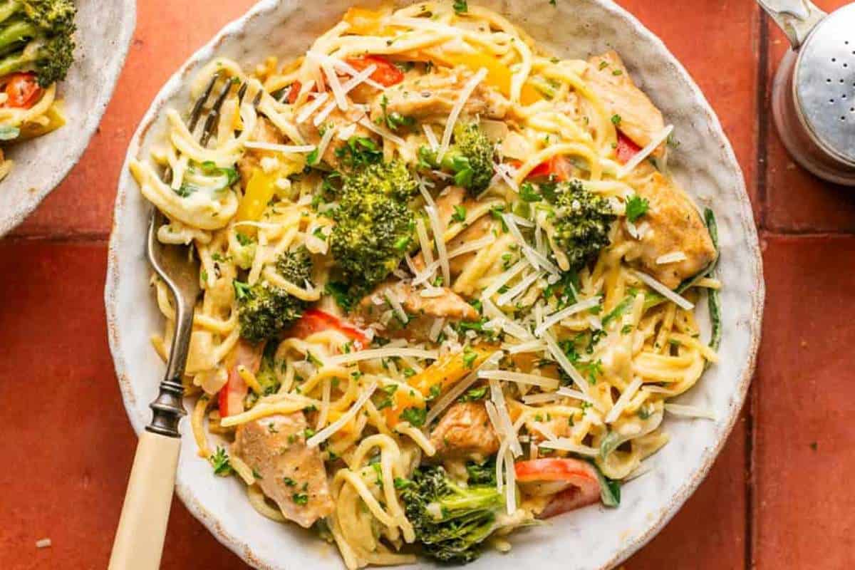 Plate of creamy chicken pasta with broccoli and tomatoes.