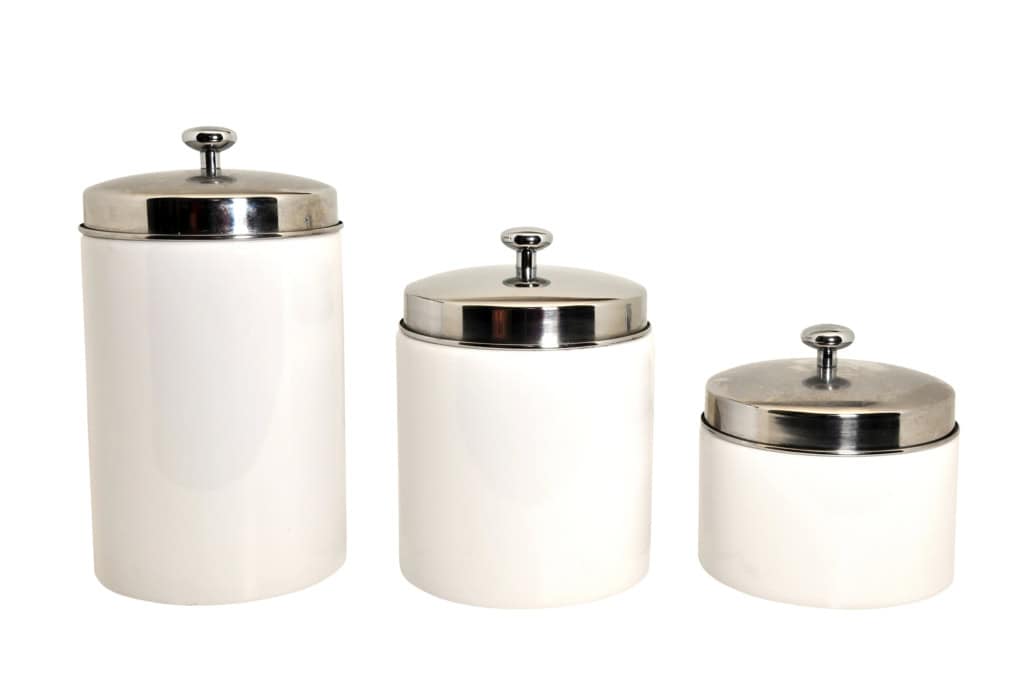 Three white kitchen canisters of varying sizes with stainless steel lids, isolated on a white background.