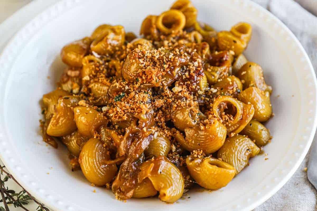A plate of pasta with a garnish, possibly breadcrumbs or grated cheese, on top.