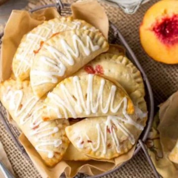 Handmade peach pastries with icing on a rustic table setting.