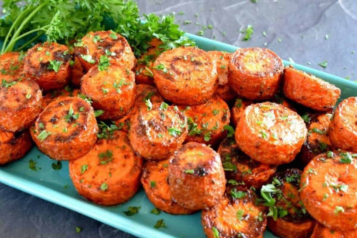 A platter of roasted carrot slices garnished with parsley, served on a blue dish.