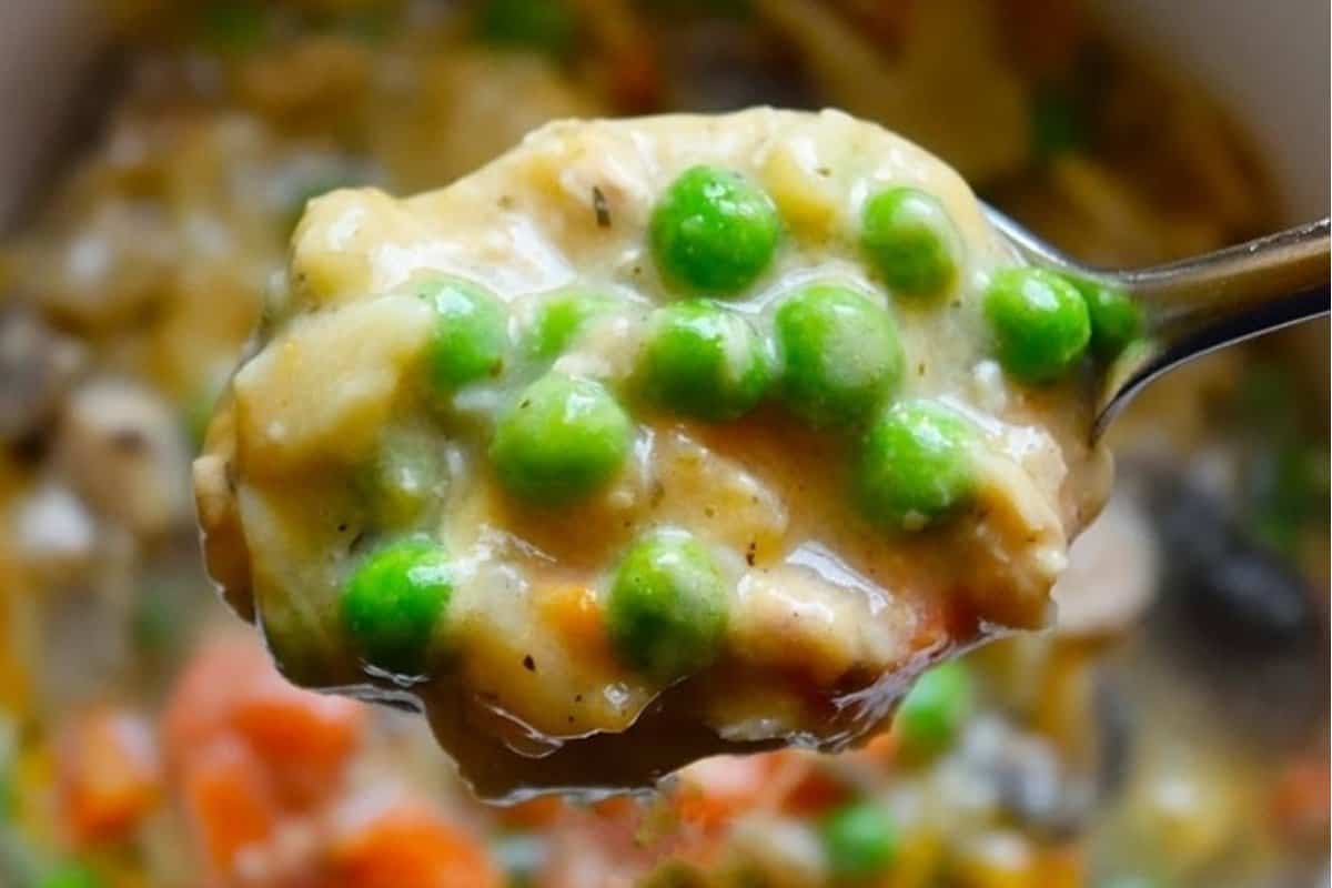 A spoonful of creamy soup with green peas and other vegetables close-up.