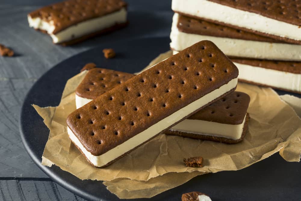 Stack of ice cream sandwiches and igloos on a plate with parchment paper.