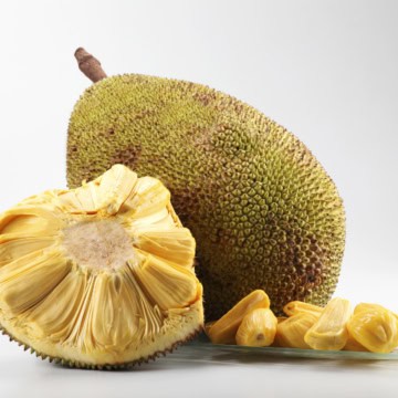 Whole and sliced jackfruit with visible seeds on a light background.