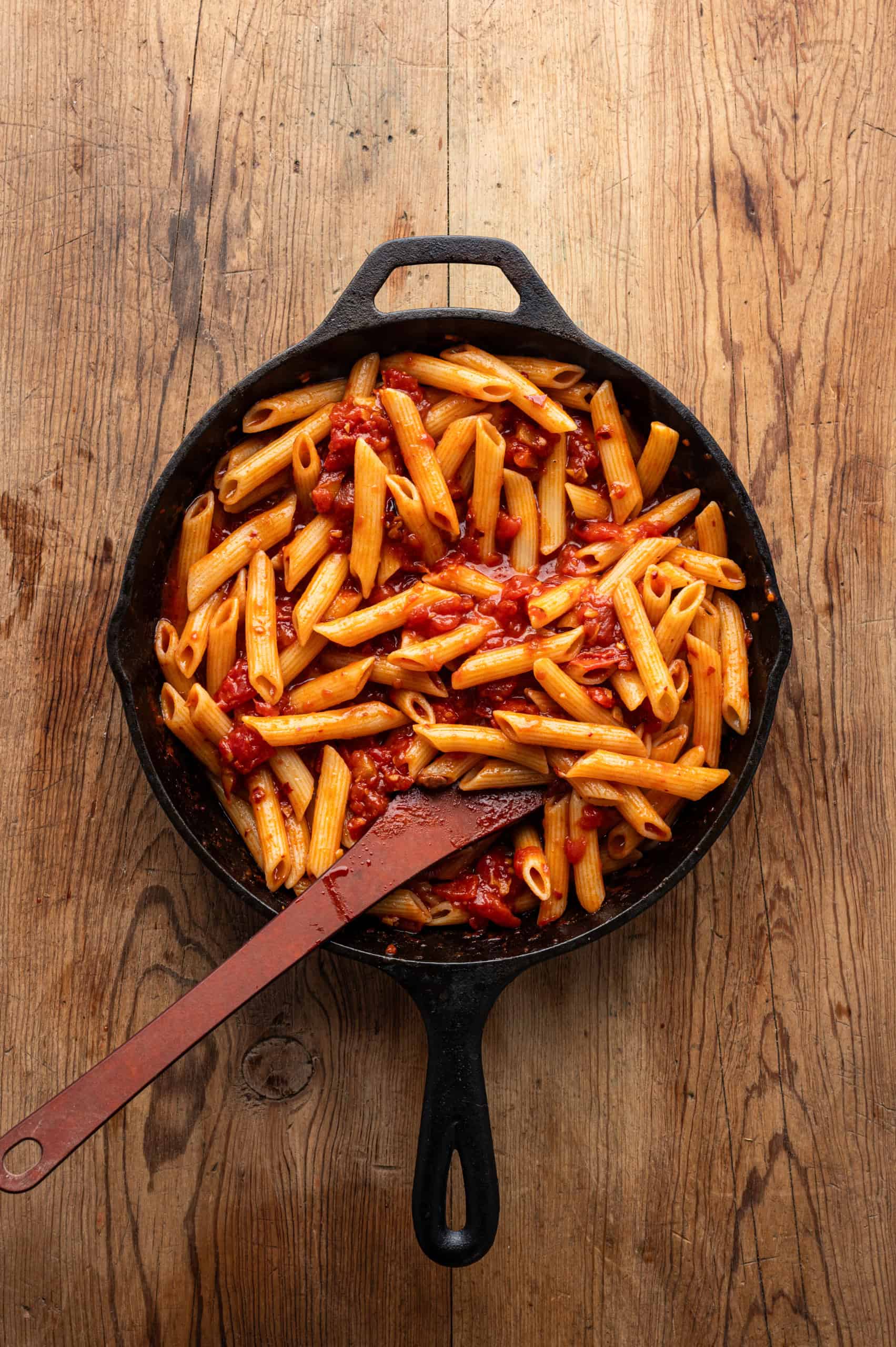 penne mixed with sauce in a pan