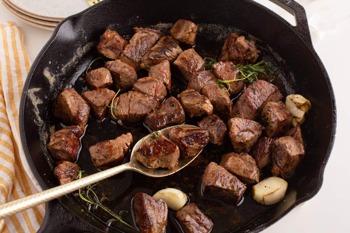 steak tips in a cast iron pan with garlic