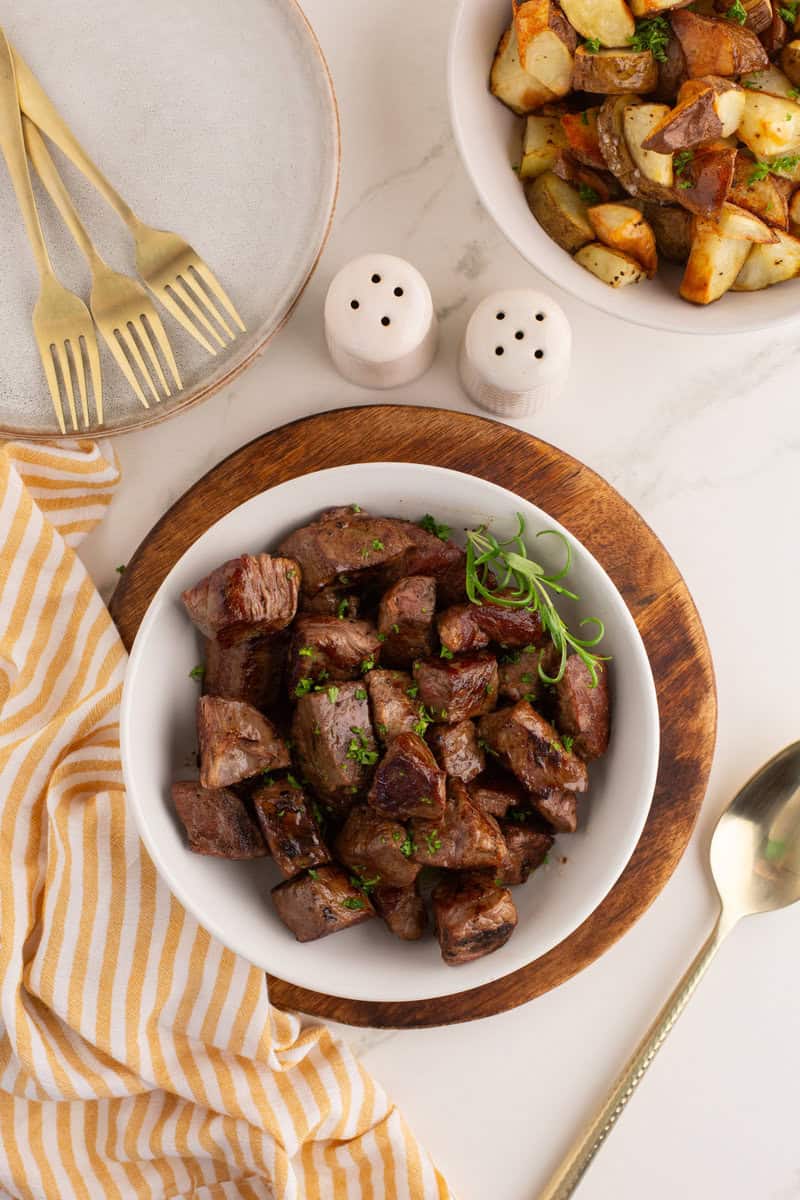steak tips on a white plate with potatoes on the side