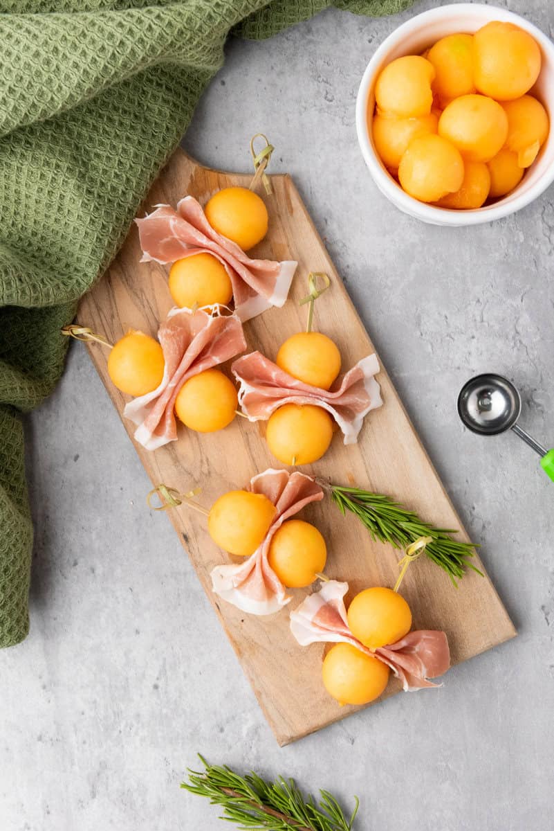 melon and prosciutto bites on a cutting board