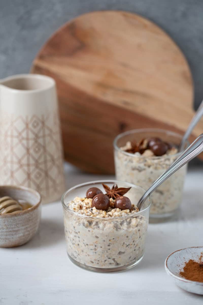 two jars of overnight oats with chocolate on top and spoons