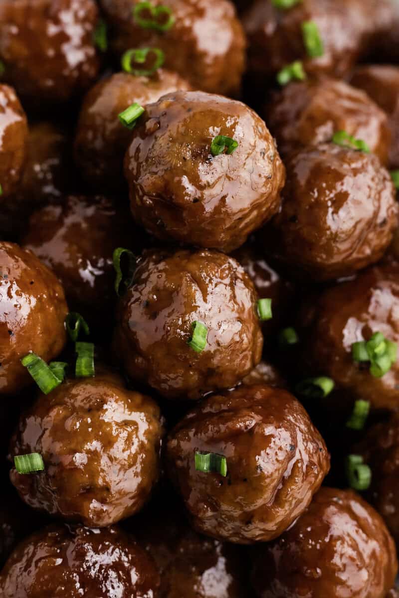 A close-up of glazed meatballs topped with chopped green onions.